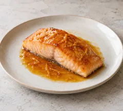 Pavé de saumon laqué, surface brillante orangée et fine sauce à la clémentine