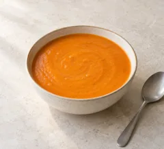 Velouté orangé de maïs et poivron rôti, surface lisse dans un bol
