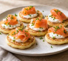 Petits blinis dorés garnis de crème citronnée, saumon fumé et ciboulette